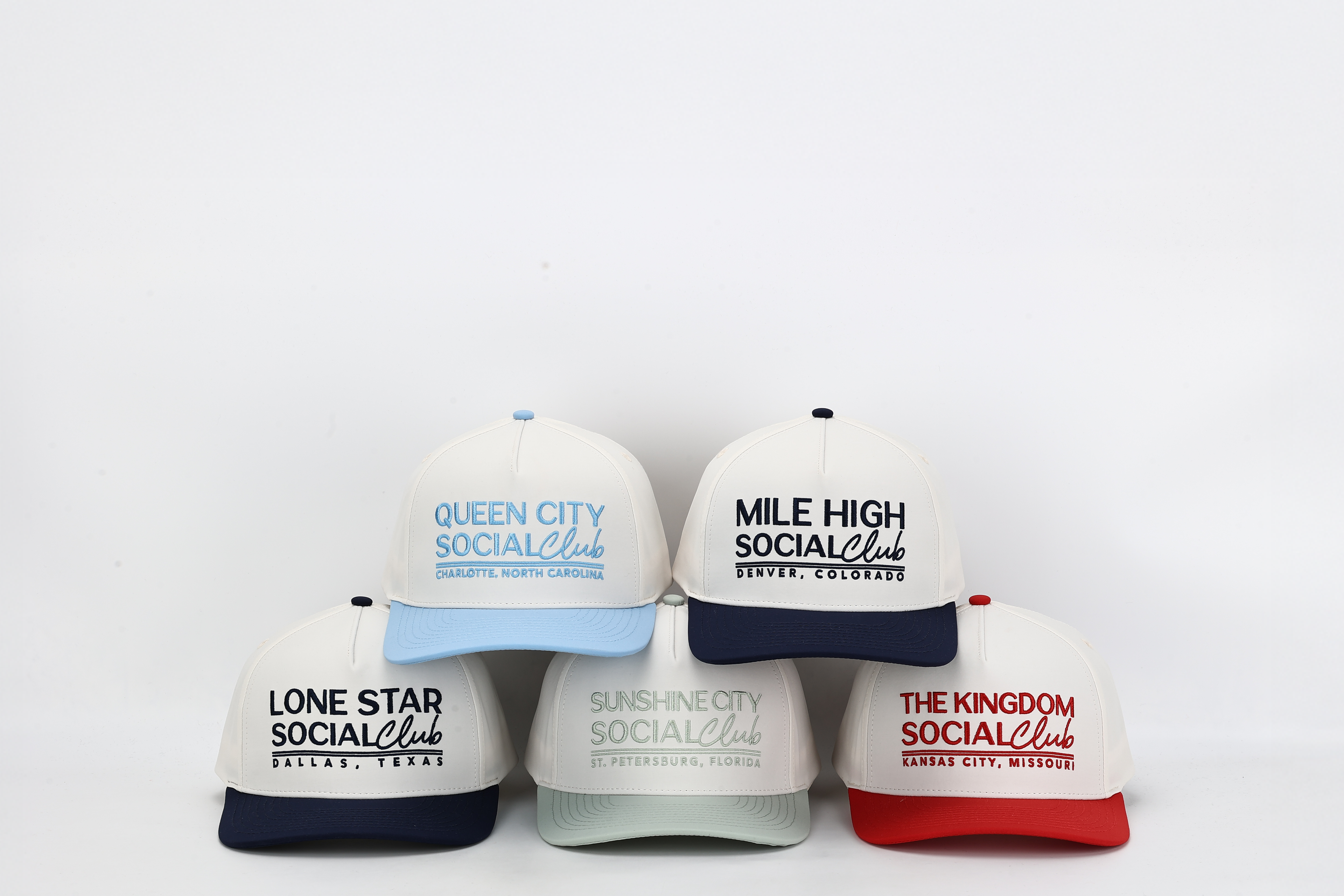 Five baseball caps with different city names and colors on a white background